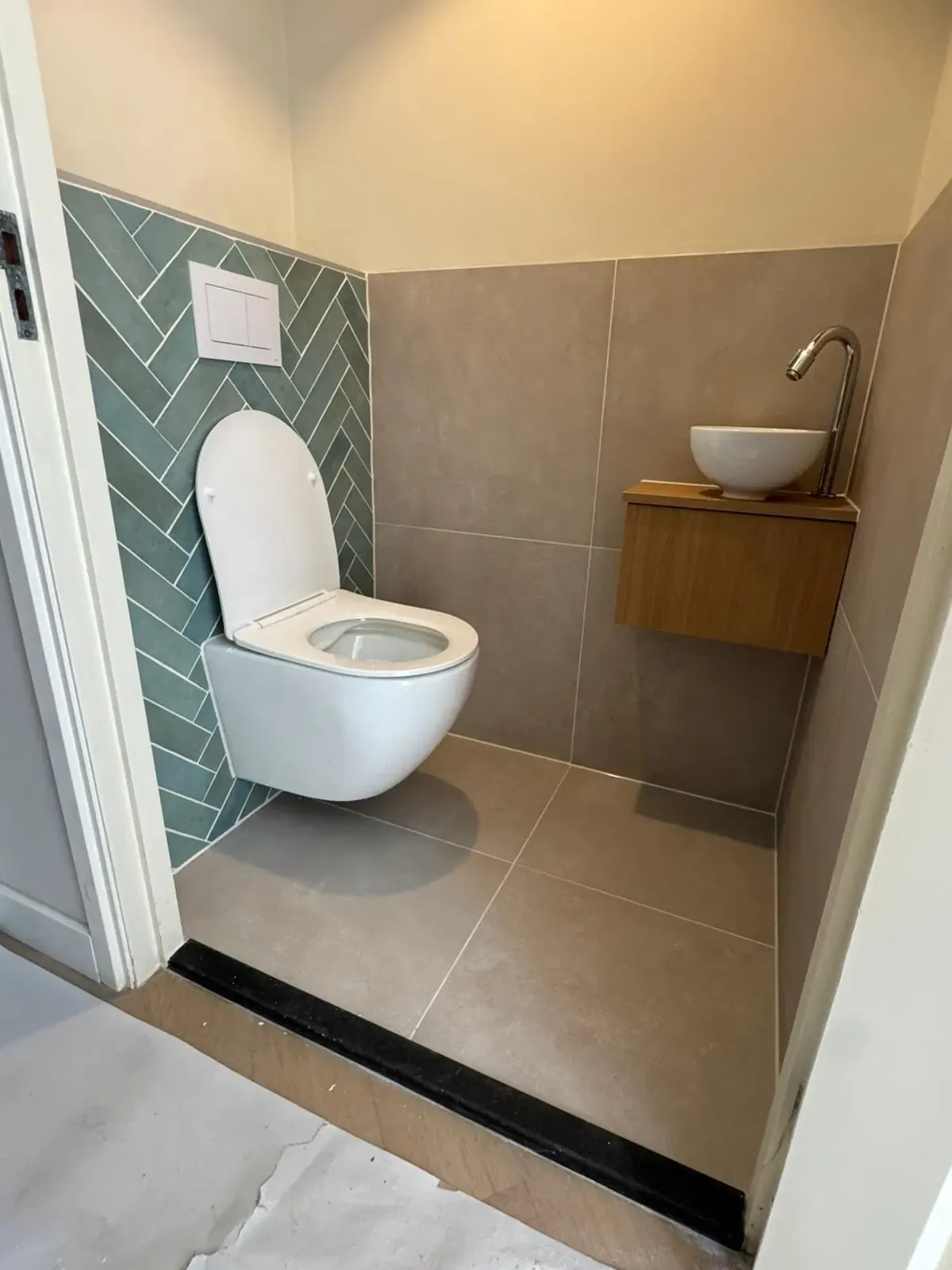 Toilet met groene wandtegels in visgraat