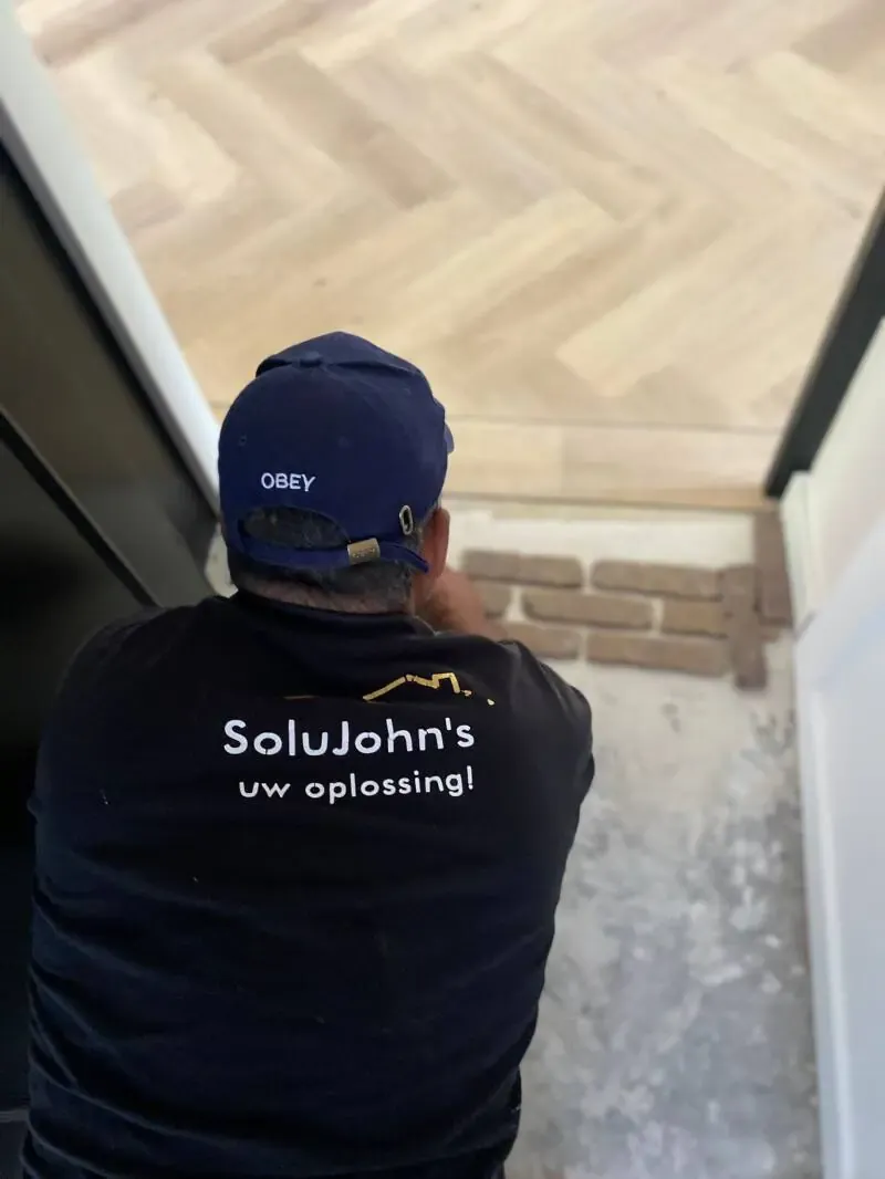 Vakman in werkshirt met de tekst SoluJohn's, uw oplossing